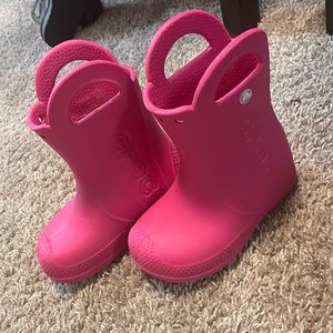 Pink Crocs rain boots.